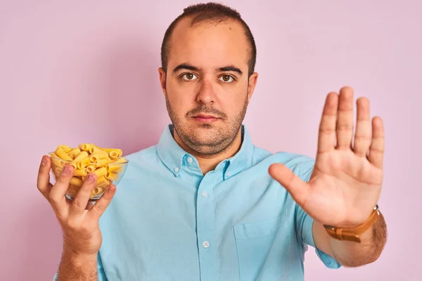 Jonge Man Holding Bowl Met Macaroni Pasta Staande Geïsoleerde Roze — Stockfoto