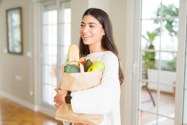 Schöne junge Frau lächelt und hält eine Papiertüte voller frischer — Stockfoto