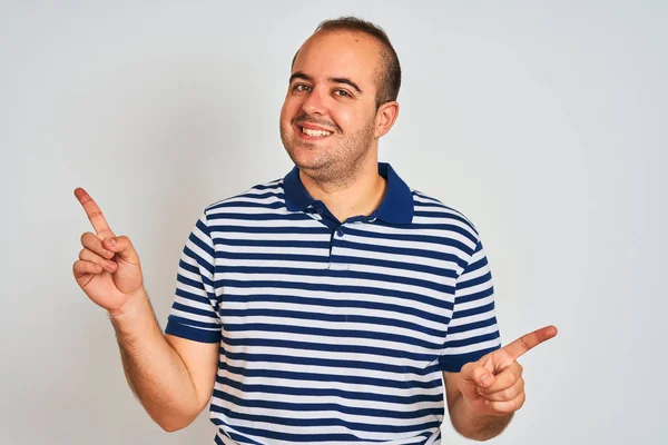 Izole beyaz arka plan üzerinde duran rahat çizgili polo giyen genç adam farklı yönlere parmakları ile işaret emin gülümseyerek. Reklam için kopya alanı