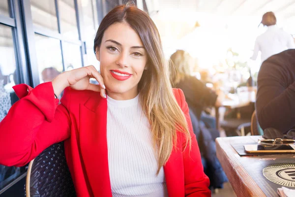 Schöne junge Frau lächelt fröhlich im Restaurant sitzend — Stockfoto