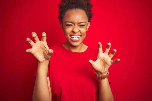 Young beautiful african american woman with afro hair over isolated red background smiling funny doing claw gesture as cat, aggressive and sexy expression
