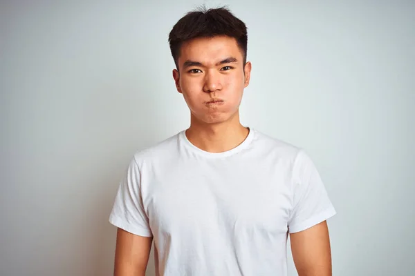 孤立した白い背景の上に立つTシャツを着た若いアジアの中国人男性は おかしな顔で頬をふくらませます 空気で膨らんだ口 クレイジーな表情 — ストック写真