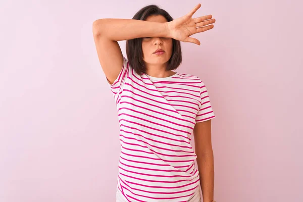 年轻的漂亮女人穿着条纹T恤站在孤立的粉红色背景上 用手臂遮住眼睛 看起来严肃而悲伤 无视力 隐藏和拒绝概念 — 图库照片