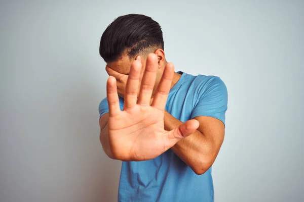 年轻的巴西男子穿着蓝色T恤站在孤立的白色背景上 双手遮住眼睛 用悲伤和恐惧的表情做停止手势 尴尬和消极的概念 — 图库照片