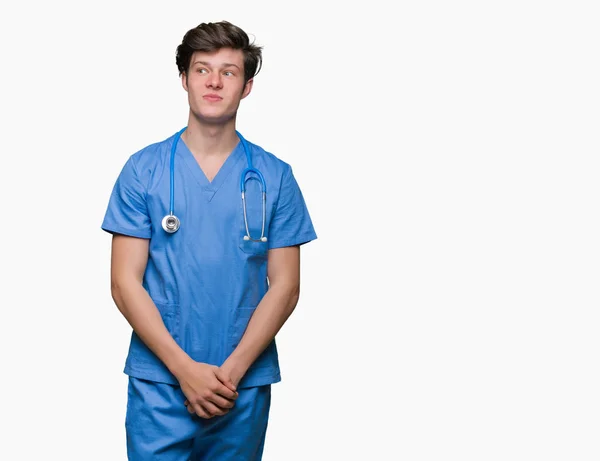 Jovem Médico Vestindo Uniforme Médico Sobre Fundo Isolado Sorrindo Lado — Fotografia de Stock