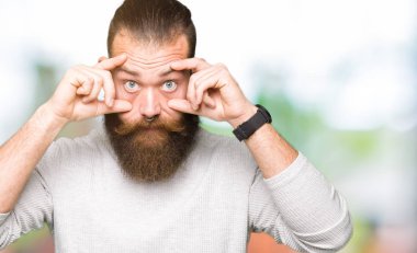 Rahat kazak giyen genç sarışın adam parmaklarıyla gözleri açmaya çalışıyor, uykulu ve yorgun sabah yorgunluğu için