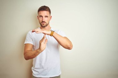İzole arka plan yapıyor zaman aşımı jest elle, sinirli ve ciddi bir yüz üzerinden Casual beyaz t-shirt giyen genç yakışıklı adam