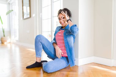 Gülümseyen, parmakları ile mutlu yüz üzerinden seyir göz el ile ok jest yapıyor katta oturan afro saçlı güzel genç Afro-Amerikan kadın.