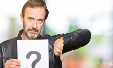 Yakışıklı orta yaş adam öfkeli yüz ile soru işareti ile kağıt tutarak, negatif işareti başparmak aşağı ile sevmediğim gösteren, ret kavramı