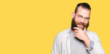 Genç sarışın adam gözlüklü emin çapraz kollar ve çeneme kaldırdı el ile gülümseme ile kameraya bakıyor. Pozitif düşünce.