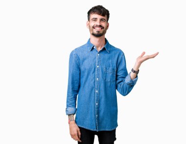 Genç yakışıklı adam neşeli sunulması ve kameraya bakarak avucunun ile işaret gülümseyen izole arka plan üzerinde.