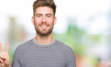 Çizgili süveter gösterme ve parmakları ile işaret giyen genç yakışıklı adam ikincisi ise kendinden emin ve mutlu gülümseyerek.