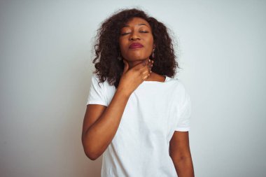 Genç afro-Amerikan kadın izole beyaz arka plan üzerinde duran t-shirt giyen ağrılı boyun dokunmadan, grip, clod ve enfeksiyon için boğaz ağrısı