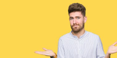 Yakışıklı delikanlı clueless ve şaşkın bir ifadeyle kollar ve eller kaldırdı. Şüphe kavramı.