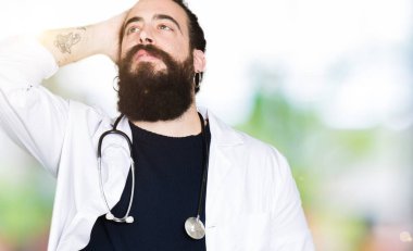 Doktor uzun saçlı tıbbi ceket ve yukarı hareketi el ile kendine güvenen dokunaklı saç gülümseyerek, çekici poz stetoskop