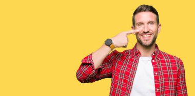 Yakışıklı adam rahat gömlek giymiş el ile işaret parmak yüz ve burun, neşeli gülümseyen