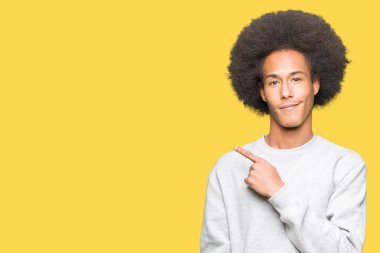 Sportif sweatshirt giyen afro saçlı genç Afro-Amerikan adam eliyle işaret parmak tarafı gösteren reklam ciddi ve sakin yüz