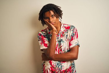 Tatilde dreadlocks ile Afro adam izole beyaz arka plan üzerinde yaz gömlek giyen yorgun görünümlü ve çapraz kolları ile depresyon sorunları ile sıkılmış düşünme.