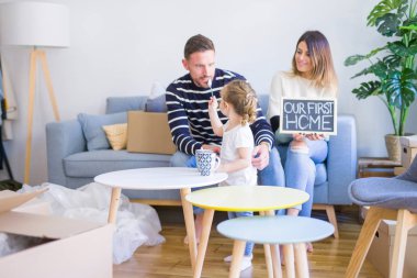 Karton kutular etrafında yeni evde kara tahta tutan kanepede oturan çocuk ile güzel famiily