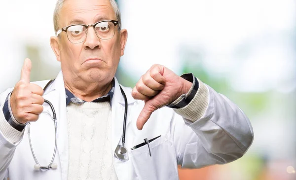 Handsome senior doctor man wearing medical coat Doing thumbs up and down, disagreement and agreement expression. Crazy conflict