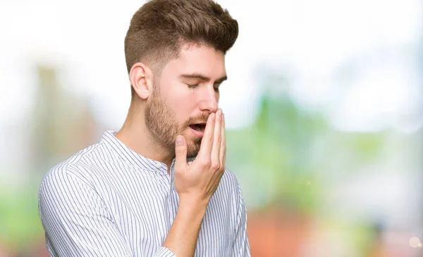 Young handsome man bored yawning tired covering mouth with hand. Restless and sleepiness.