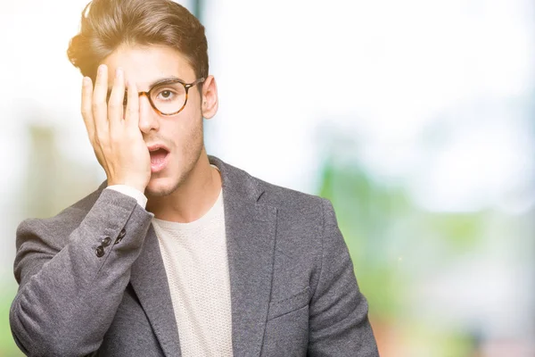 Young business man wearing glasses over isolated background Yawning tired covering half face, eye and mouth with hand. Face hurts in pain.