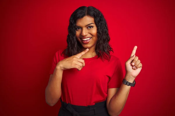 Beautiful transsexual transgender woman wearing t-shirt over isolated red background smiling and looking at the camera pointing with two hands and fingers to the side.