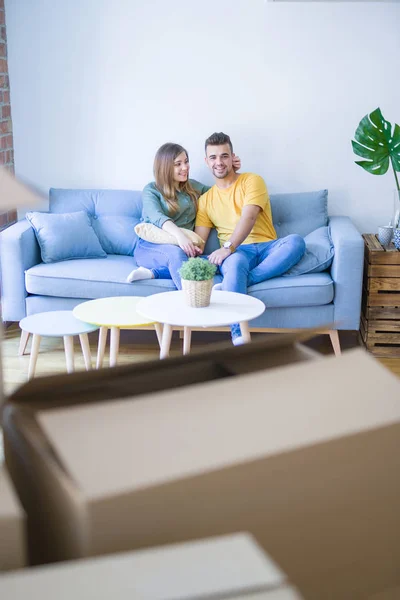年轻漂亮的夫妇坐在新公寓的张子上 拥抱着纸板箱 非常兴奋地搬到新家 — 图库照片