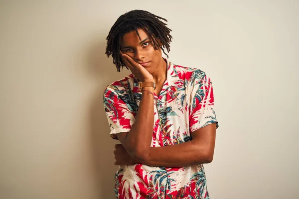 Tatilde dreadlocks ile Afro adam izole beyaz arka plan üzerinde yaz gömlek giyen yorgun görünümlü ve çapraz kolları ile depresyon sorunları ile sıkılmış düşünme.