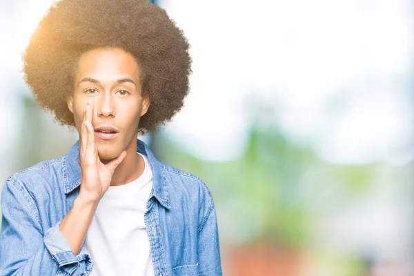 Young african american man with afro hair hand on mouth telling secret rumor, whispering malicious talk conversation