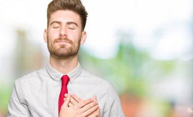 Göğüs kapalı gözlerle ellerinde ve yüzünde minnettar jest ile gülümseyen genç yakışıklı iş adamı. Sağlık kavramı.