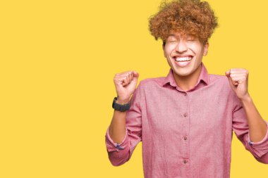 Afro saçlı genç yakışıklı iş adamı başarı için heyecanlı kolları ile zafer gülümseyerek kutluyor kaldırdı. Kazanan kavramı.