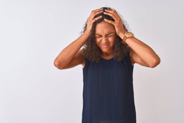 Mavi elbise giyen genç brezilyalı kadın izole beyaz arka plan üzerinde ayakta baş ağrısı umutsuz muzdarip ve stresli çünkü ağrı ve migren. Eller baş üstünde.