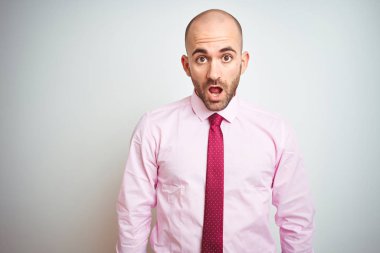 Izole arka plan üzerinde pembe kravat giyen genç iş adamı korkmuş ve sürpriz ifade, korku ve heyecanlı yüz ile şok.