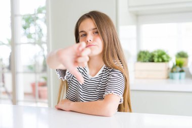 Çizgili t-shirt giyen güzel genç kız çocuk mutsuz ve kızgın gösteren reddi gösteren ve aşağı jest başparmak ile negatif. Kötü ifade.