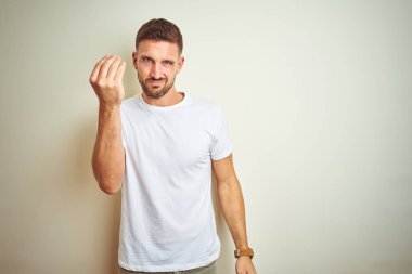 El ve parmak ile İtalyan jest yapıyor emin ifade izole arka plan üzerinde rahat beyaz t-shirt giyen genç yakışıklı adam