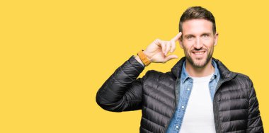 Kışlık palto giyen yakışıklı adam Tek parmakla baş gösteren gülümseyen, harika bir fikir ya da düşünce, iyi bellek