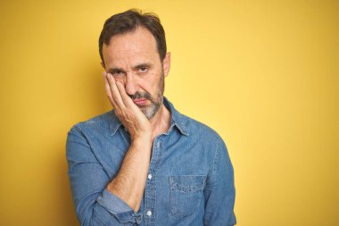 Izole sarı arka plan üzerinde gri saçlı yakışıklı orta yaş yaşlı adam yorgun görünümlü ve çapraz kolları ile depresyon sorunları ile sıkılmış düşünme.