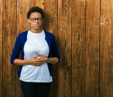 Genç güzel Afrikalı-Amerikalı kadın üzerinde gözlük takan izole mide üzerinde el ile arka plan çünkü hazımsızlık, ağrılı hastalık hasta hissediyor. Ağrısı kavramı.