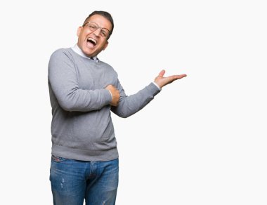 Orta yaş bussines Arap adam gözlüklü üzerinde arka izole el ve reklam mutlu ve kendinden emin gülümseyen sunulması avuç, yanında işaret