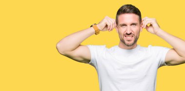 Rahat beyaz t-shirt giyen yakışıklı adam parmaklar, komik jest ile kulakları çekerek gülümsüyor. Audition sorunu