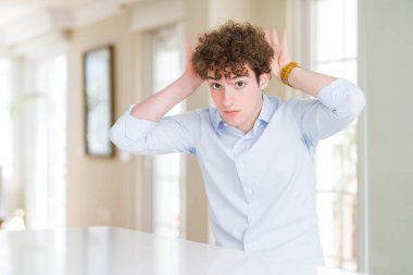 Kıvırcık okumak kafa ile genç iş adamı alaycı ve şüpheci görünümlü avuç içi ile tavşan kulakları jest yapıyor. Paskalya tavşanı kavramı.