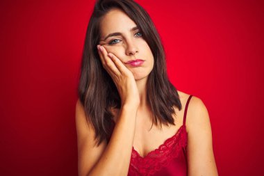 Genç güzel kadın kırmızı izole arka plan üzerinde seksi iç çamaşırı giyen yorgun görünümlü ve çapraz kolları ile depresyon sorunları ile sıkılmış düşünme.