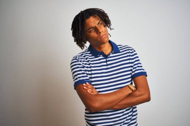 Kollu yana bakan izole beyaz arka plan üzerinde duran çizgili mavi polo giyen dreadlocks giyen Afro adam ikna ve kendinden emin geçti