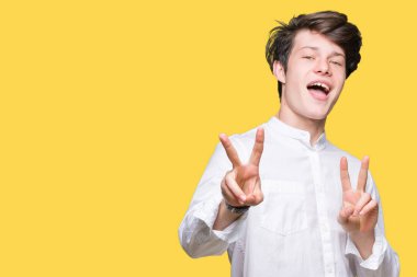 Genç yakışıklı iş adamı zafer işareti yapıyor parmak gösterilen kamera seyir gülümseyen izole arka plan üzerinde. İki numaralı.