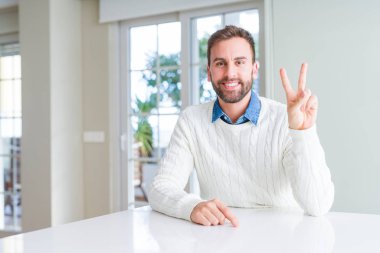 Yakışıklı adam rahat kazak gösteren giyen ve emin ve mutlu gülümserken parmakları ile iki numara işaret.