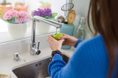 Genç kadın lavabo su kullanarak sebze ve meyve yıkama