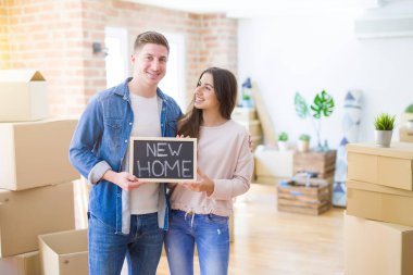 Güzel genç çift aşık ve yeni bir ev için mutlu gülümseyen yeni bir eve hareketli tahta tutarak sarılmak