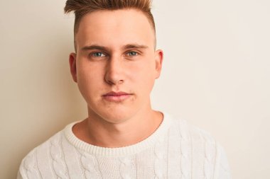 Genç yakışıklı adam ciddi düşünme akıllı yüz üzerinde kendine güvenen bir ifade ile izole beyaz arka plan üzerinde duran rahat t-shirt giyiyor