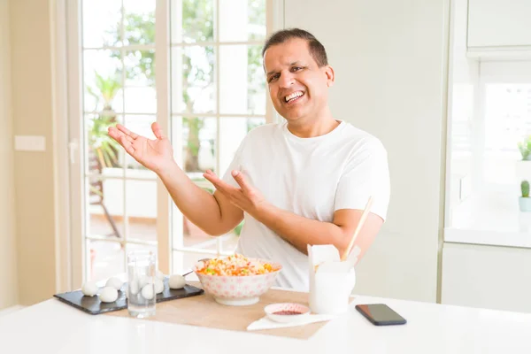 Midaldrende Mand Spiser Asiatisk Mad Med Spisepinde Derhjemme Forbløffet Smilende - Stock-foto